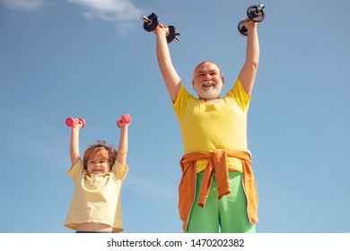 Grandfather Helping Kid Exercising With Dumbbells. Senior Man And Child In Family Health Club. Father And Son Spotting