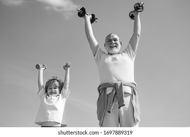 Grandfather Helping Kid Exercising With Dumbbells. Senior Man And Child In Family Health Club. Father And Son Spotting