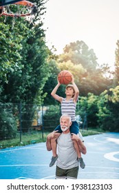 Grandfather and his grandson enjoying in beautiful sunny day and playing basketball.