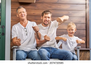 Grandfather With His Son And Grandson Are Having Fun Sitting On A Bench Near A Wooden House. Family Role-playing Games In The Fresh Air