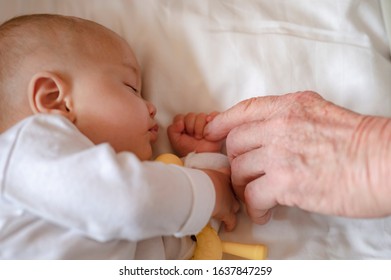 The grandfather holding hand while his newborn baby sleeping at home in holiday. Family, senior, grandson, baby, grandfather, Happy, lifestyle concept.