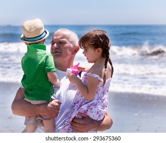 Grandfather Holding His Grandkids On A Beach Vacation