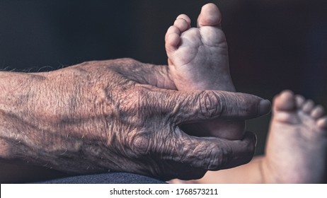 The grandfather holds little legs of his grandson 