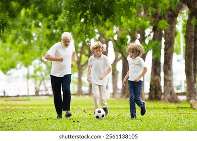 Grandfather and kids play football in sunny park. Happy family playing ball. Grandpa and children play soccer. Generation love. Active senior man with little boy. Grandchildren visit grandparents. - Powered by Shutterstock