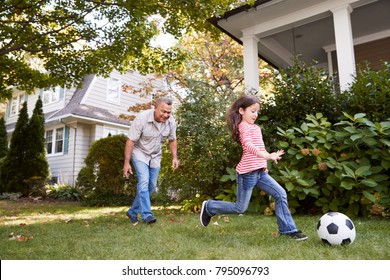 Grandfather Playing Soccer In Garden With Granddaughter