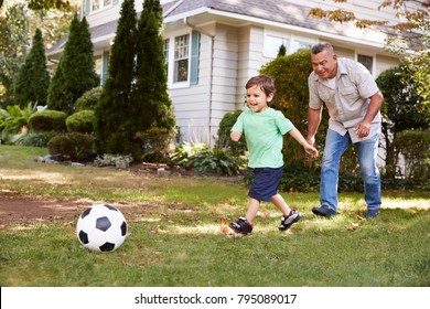 Grandfather Playing Soccer In Garden With Grandson