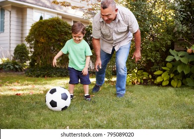 Grandfather Playing Soccer In Garden With Grandson