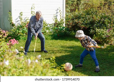 Grandfather Plays With His Grandson In Nature In Summertime. Elderly Father Plays Sports With His Son On Their Day Off. Family Outdoor Activities On Vacation.