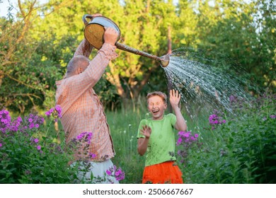 The grandfather pours water on his grandson from a watering can, and the grandson rejoices and laughs. The father and son enjoy playing and communicating with each other. - Powered by Shutterstock