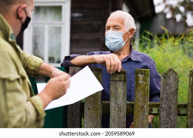 Grandfather In Protective Mask Talking To Census Agent Standing At The Fence Of His Country House