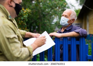 Grandfather In Protective Mask Talking To Census Agent Standing At The Fence Of His Country House