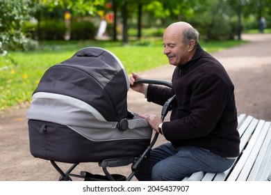 Grandfather Pushing Newborn In Stroller In Park