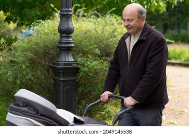 Grandfather Pushing Newborn In Stroller In Park