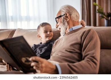 A grandfather is reading a book to his grandchild at home. - Powered by Shutterstock