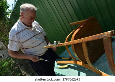 Grandfather Repairs A Chair On The Street, Using Screws, Glue, And A Vice.