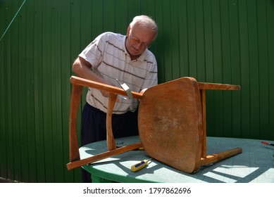 Grandfather Repairs A Chair On The Street, Using Screws, Glue, And A Vice.