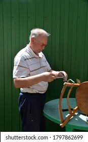 Grandfather Repairs A Chair On The Street, Using Screws, Glue, And A Vice.