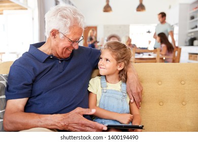 Grandfather Sitting With Granddaughter On Sofa Using Digital Tablet At Home - Powered by Shutterstock