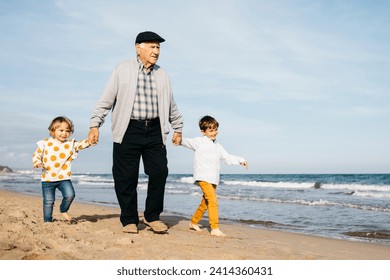 Grandfather strolling with his grandchildren hand in hand on the beach - Powered by Shutterstock