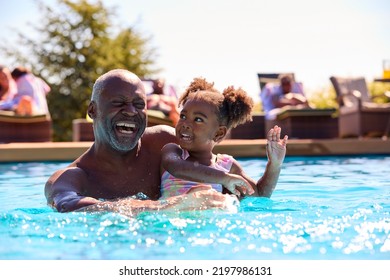 Grandfather Teaching Granddaughter To Swim In Outdoor Pool On Holiday - Powered by Shutterstock