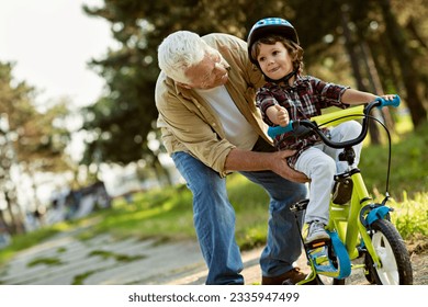 Grandfather teaching his grandson how to ride a bike in the park - Powered by Shutterstock