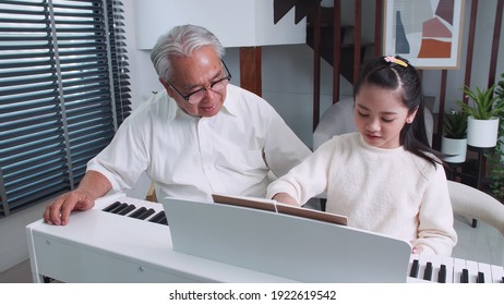 Großvater bringt kleine Enkelin bei, zu Hause Klavier zu spielen.
