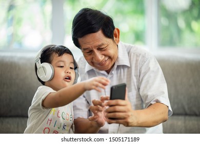 Grandfather tech grandson listen music on smartphone