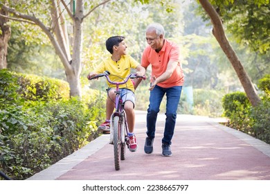 Grandfather trying to teach grandson to ride a cycle at park. - Powered by Shutterstock