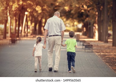 Grandfather with two kids walking in the autumn park