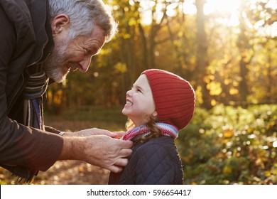 Grandfather Tying Granddaughter's Scarf On Autumn Walk