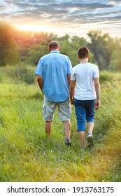 Grandfather walks with his teenage grandson in nature. Two generations. Male conversations. Parenting. Childhood. Family trip with children. Summer. Family values ​​concept.