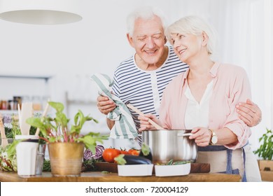 Grandfather Is Watching Grandma Who Mixes Vegetable Soup In A Pot During Cooking Dinner