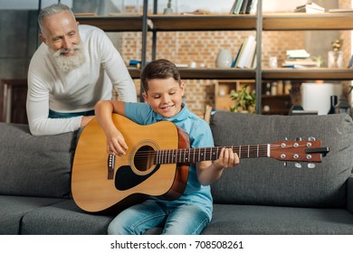 Grandfather watching his grandson play guitar - Powered by Shutterstock