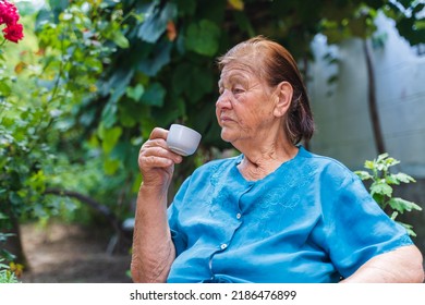 Grandma Drinking Coffee Outside In Her House Garden During The Day