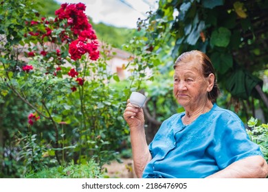 Grandma Drinking Coffee Outside In Her House Garden During The Day