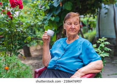 Grandma Drinking Coffee Outside In Her House Garden During The Day