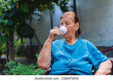 Grandma Drinking Coffee Outside In Her House Garden During The Day