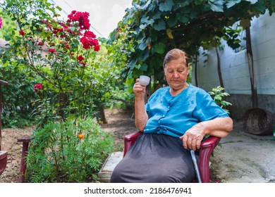 Grandma Drinking Coffee Outside In Her House Garden During The Day