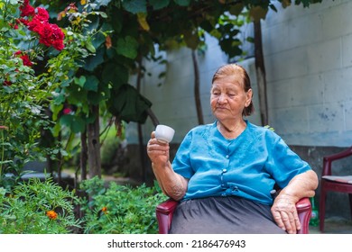 Grandma Drinking Coffee Outside In Her House Garden During The Day