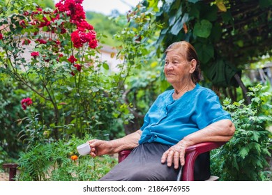 Grandma Drinking Coffee Outside In Her House Garden During The Day