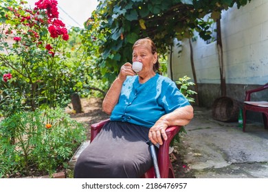 Grandma Drinking Coffee Outside In Her House Garden During The Day