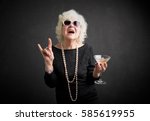 Grandma with glasses and drink in hand showing rock sign 
