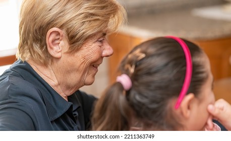 Grandma And Grand Daughter At Home Looking At Something On The Screen.