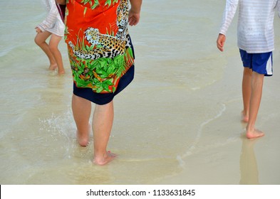 Grandma And Grandchildren Walking On The Beach On A Vacation In A Tropical Destination. Multi Generational Family On A Trip.