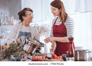 Grandma And Granddaughter Cooking Tomato Soup In The Kitchen