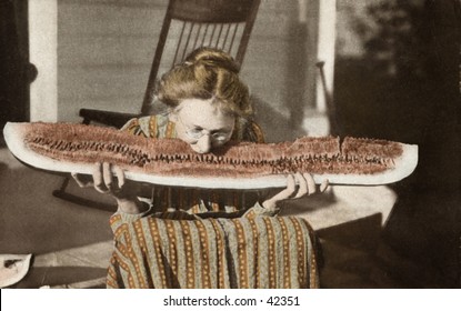 Grandma Pigs Out - a circa 1900 hand-tinted black & white photograph of grandma, on the front porch, pigging-out on a HUGE slice of watermelon.