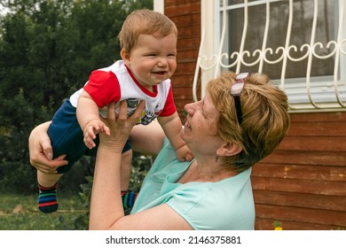 grandma plays with her grandson in the garden in the village