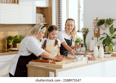 Grandma Spending Time With Grandaughter Teaching Kneading Dough For Baking Cooking Homemade Piza Pasta Bread Cookies Biscuits In Modern Light Kitchen. Happy Young Mother Helping Managing Process.