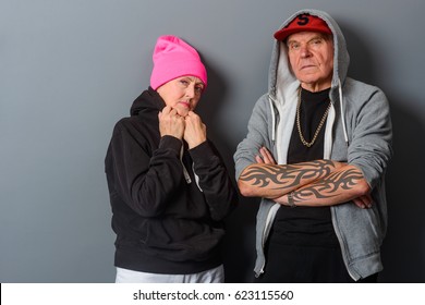 Grandma Straightens Her Collar, Grandpa's Got His Tattooed Arms Crossed. Unfriendly Attitude Of Old Gangstas. Don't Mess With These Pensioners.