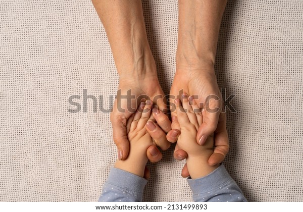 Grandma\'s hands are holding baby\'s hands.\
Concept taking care of the baby , soft skin, great-grandmother and\
great-grandson.